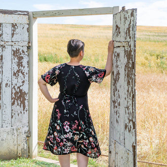Person wearing Robe blouse portefeuille, 34 au 56, 4 statures – Sésame, patron de couture pdf à télécharger, in a field.
