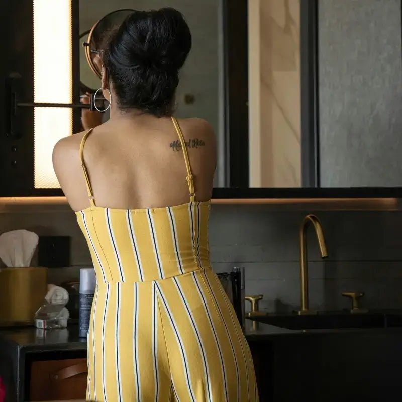 Femme portant une combinaison rayée jaune devant un miroir, illustrant les Patrons de Combinaisons Femme, collection de patrons de couture pdf à télécharger.