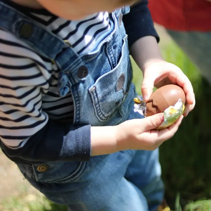 Enfant découvrant un œuf en chocolat, parfait pour utiliser avec les Patrons de couture pour Pâques dans une ambiance festive.