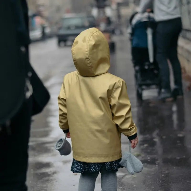 Enfant portant un manteau par temps pluvieux, illustrant la collection de Patrons de Manteaux Enfant pour couture pdf à télécharger.