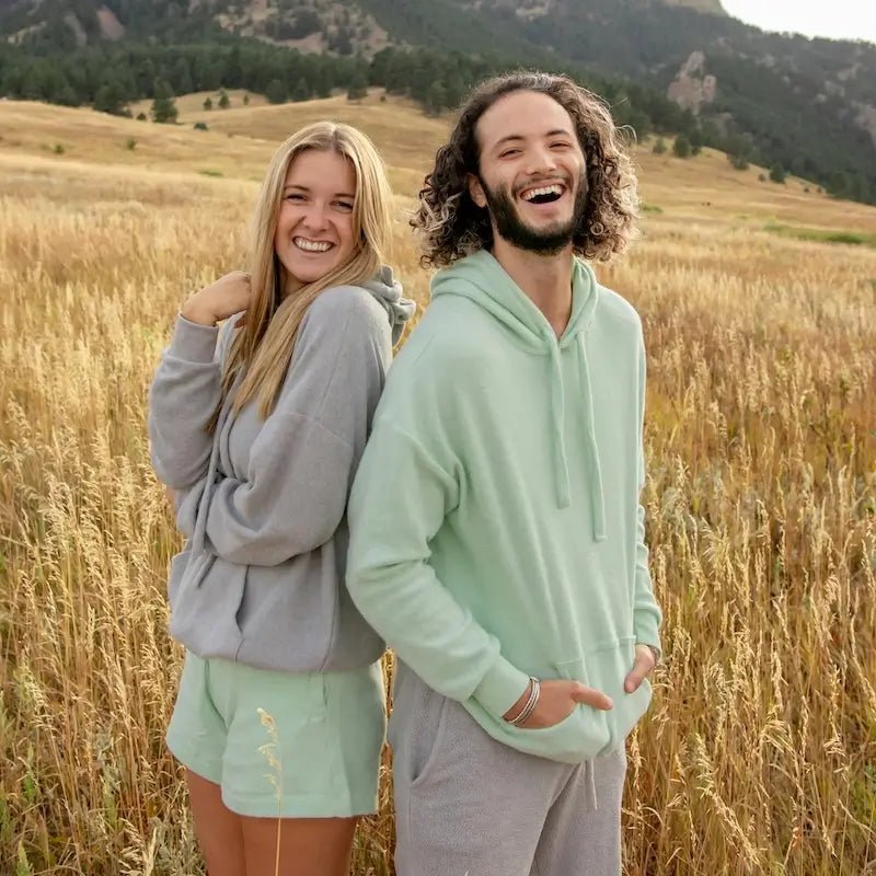 Couple souriant portant des sweats dans un champ, illustrant la collection de Patrons de Sweats