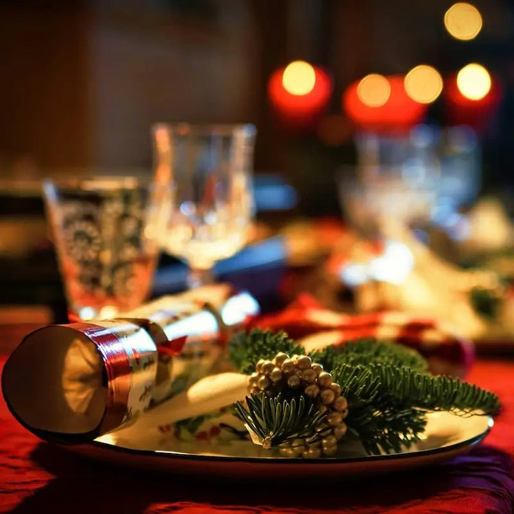 Table de fête décorée avec des bougies rouges et des branches de pin pour une ambiance chaleureuse et accueillante.
