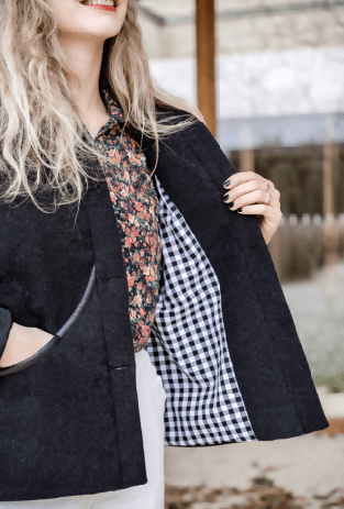 Femme souriante portant la veste NIMA, montrant sa doublure à carreaux noir et blanc, élégante et féminine.