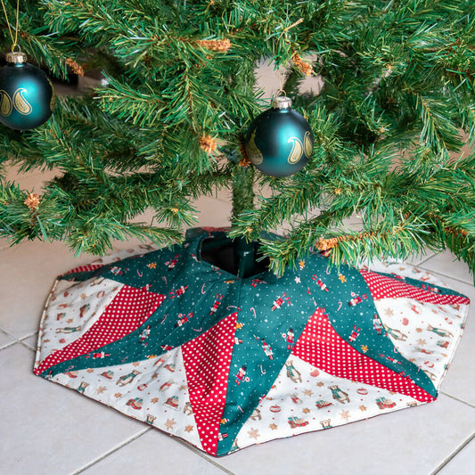 Jupe de sapin de Noël avec un motif étoilé, en tissu patchwork rouge et vert, embellissant le pied de l'arbre de Noël.