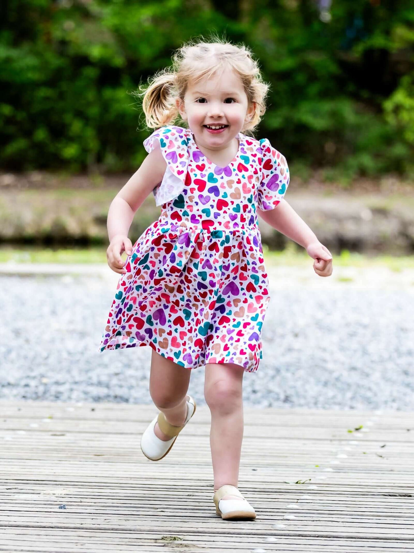 Petite fille souriante portant la robe colorée AIRELLE - La robe / blouse aux 1000 versions, patron de couture PDF à télécharger.