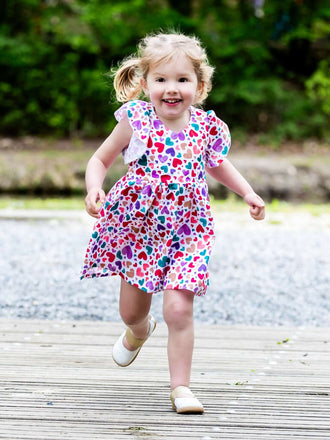 Petite fille souriante portant la robe colorée AIRELLE - La robe / blouse aux 1000 versions, patron de couture PDF à télécharger.