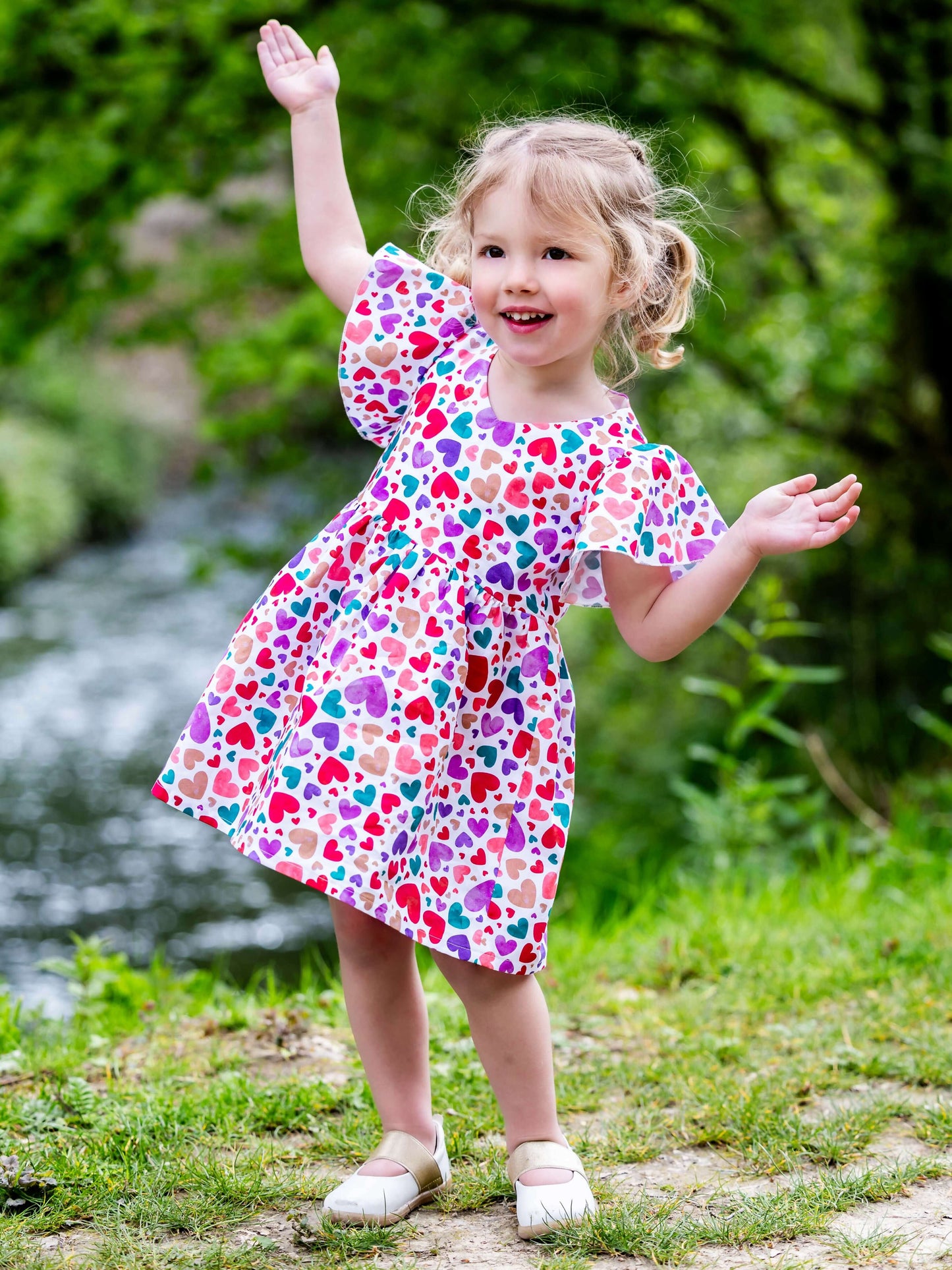 Enfant souriante portant la robe colorée Airelle au bord d'un ruisseau, patron de couture pdf à télécharger, AIRELLE - La robe / blouse aux 1000 versions.