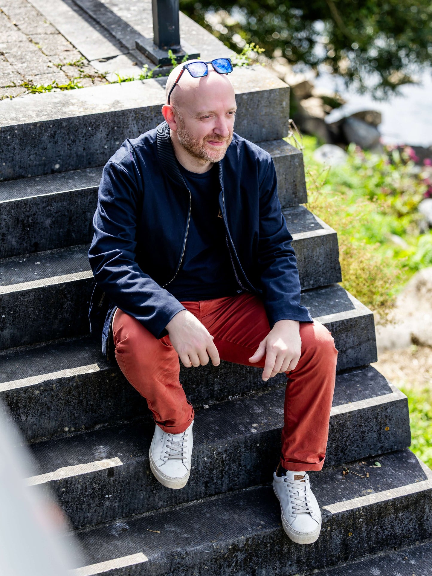 Homme assis sur des marches en extérieur portant AMANDE : le bomber. Patron de couture PDF à télécharger disponible.