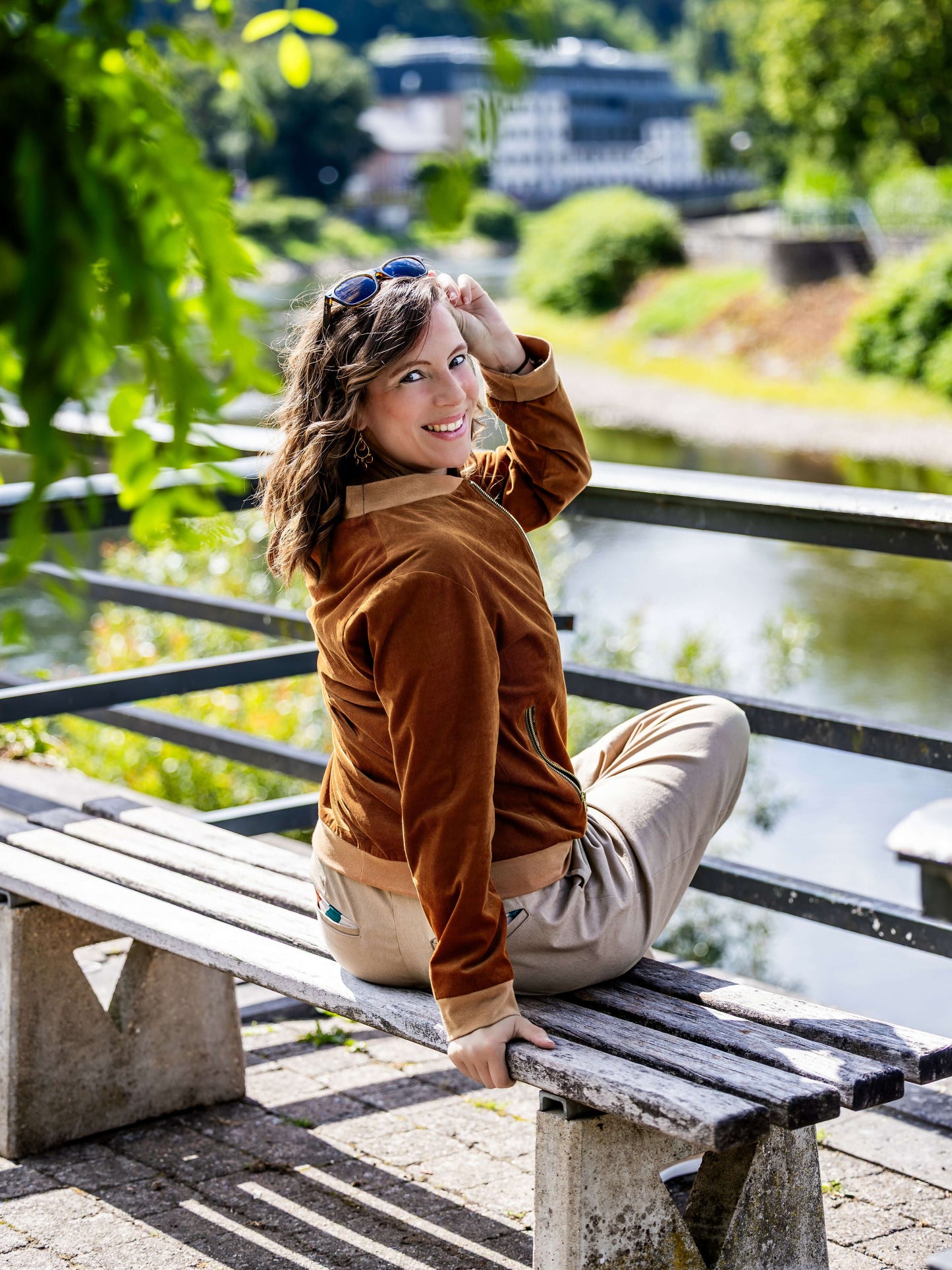 Femme portant AMANDE : le bomber assise sur un banc près de l'eau, patron de couture pdf à télécharger.