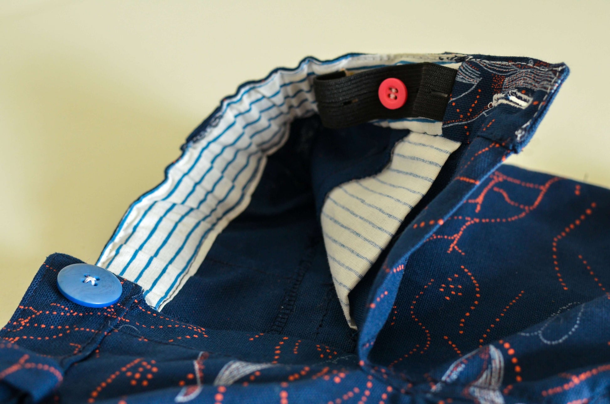 Détails du col d'une chemise avec boutons colorés, motif marine et doublure contrastée.