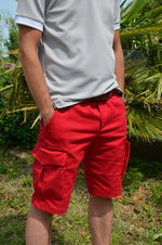 Homme portant des bermudas rouges avec poches cargo, idéal pour un style décontracté ou habillé.