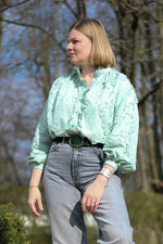 Femme portant la Blouse Anoushka verte, patron de couture pdf à télécharger, avec col montant et manches longues froncées.