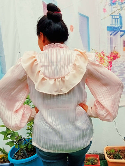 Femme portant une blouse Fulla avec col montant froncé et manches Bishop, vue de dos, jardin en arrière-plan.