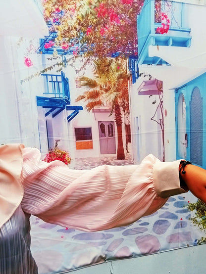 Blouse Fulla avec volants et manches Bishop, portée devant un décor méditerranéen coloré.