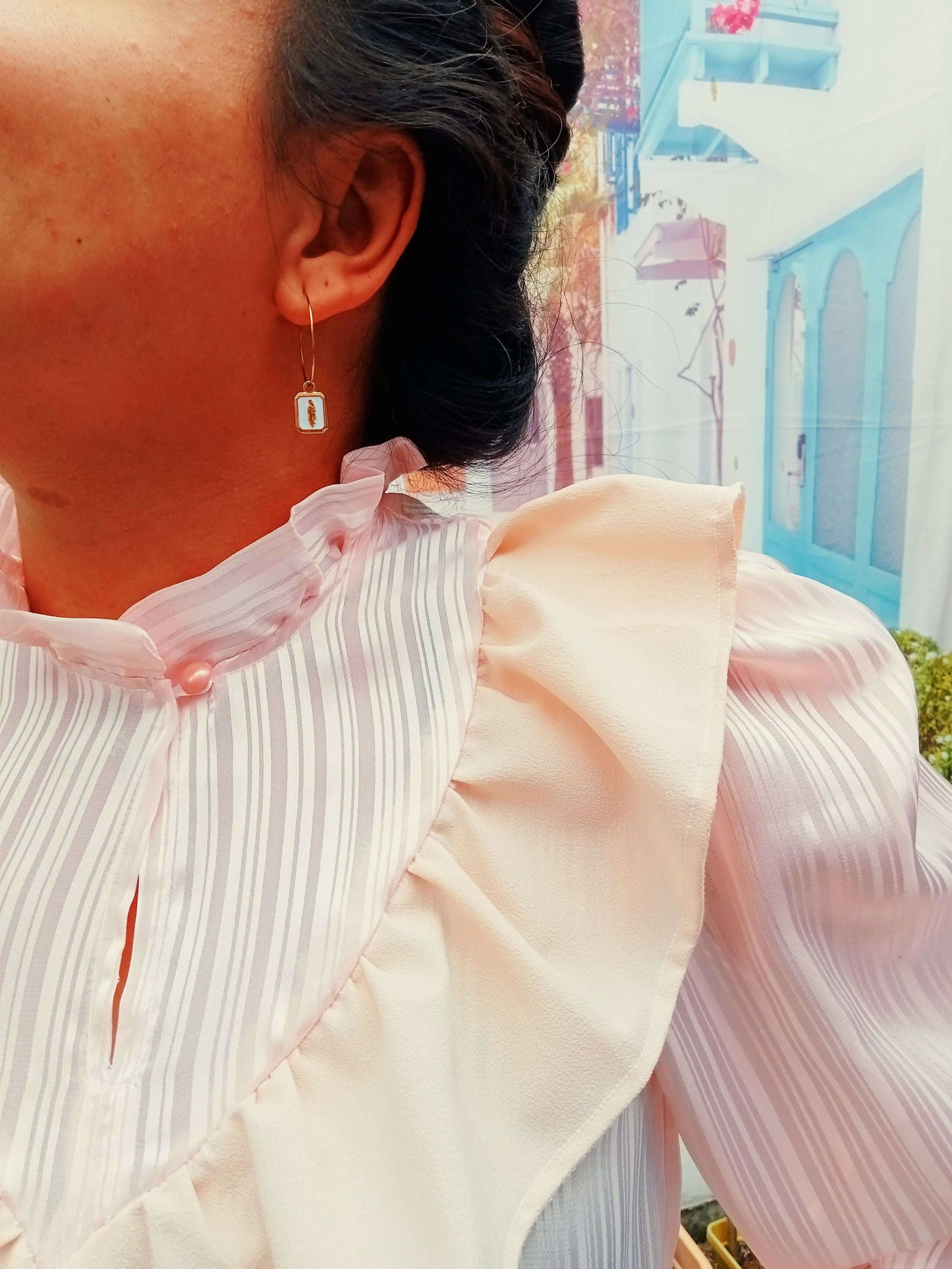 Blouse Fulla avec col montant, volants et manches Bishop, mise en scène en extérieur coloré.