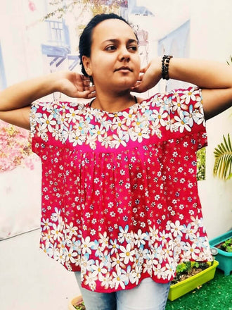 Femme portant une blouse rouge à fleurs, style ample et flou, idéale pour le printemps, en tissus léger.