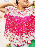 Femme souriante portant une blouse ample à fleurs roses, idéale pour un style décontracté en été.