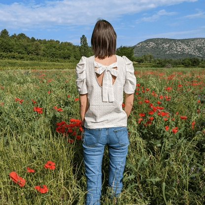 Femme portant la Blouse Quetzal | Taille 32 à 50 avec manches bouffantes et nœud délicat, patron de couture pdf à télécharger, en champ de coquelicots.