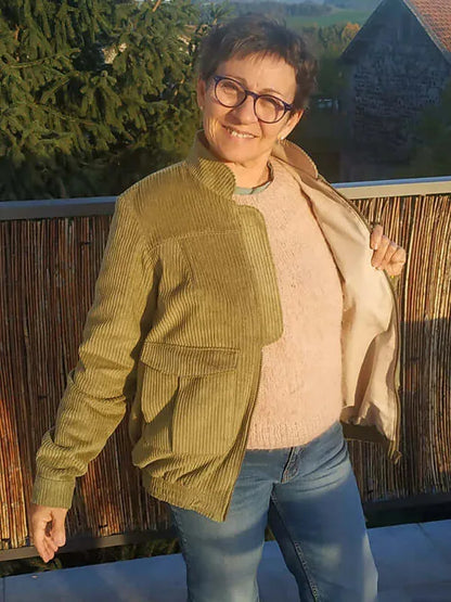 Femme portant le Patron PDF Bomber Phoenix en velours côtelé ocre, vue de face, sourire, terrasse avec vue campagne