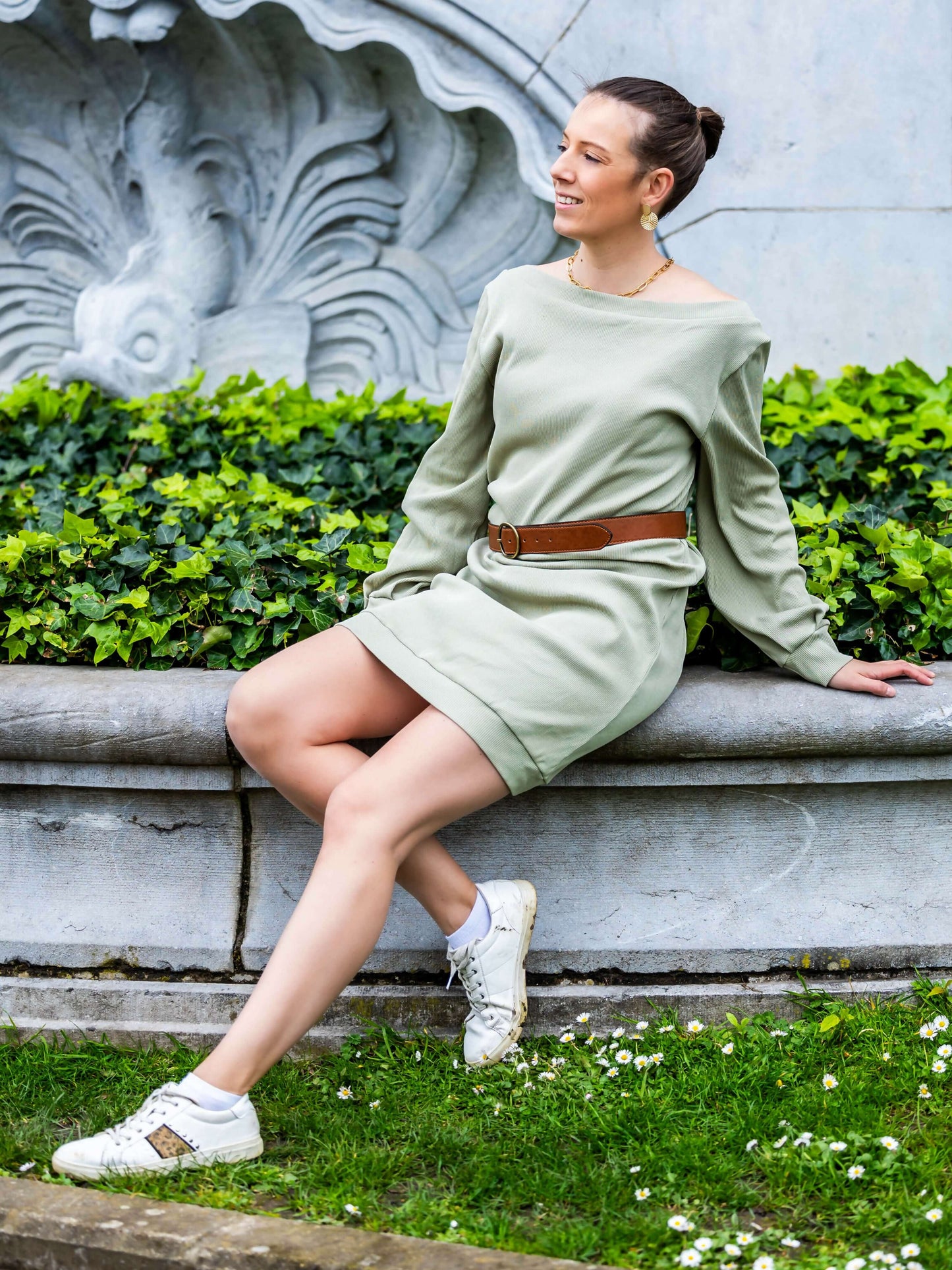 Modèle portant CACAO - LE sweat / t-shirt multi-options en vert, patron de couture pdf à télécharger, assise sur un mur en pierre.