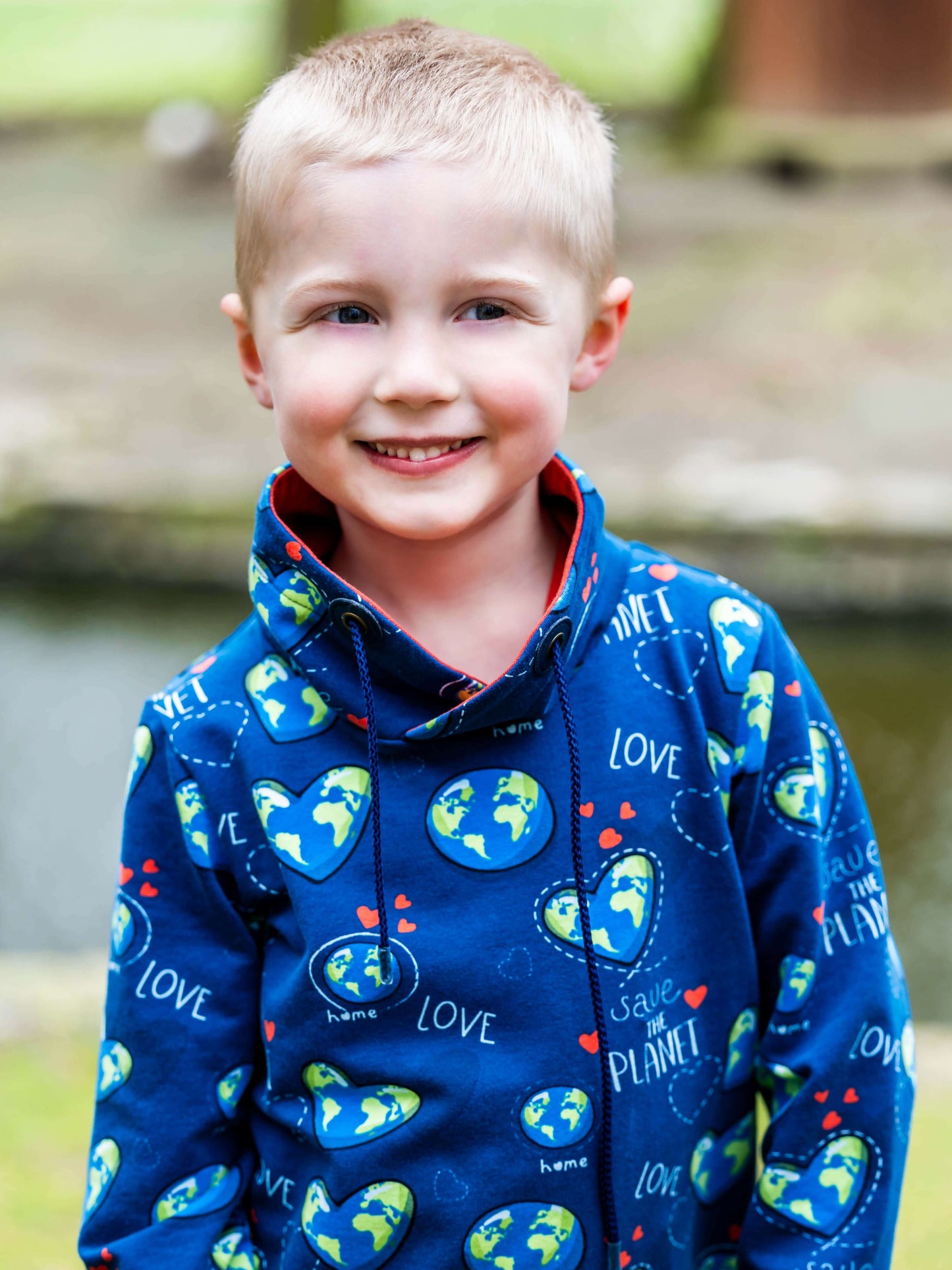 Enfant portant le sweat "Save the Planet", motif planètes et coeurs sur fond bleu, pratique et mignon.