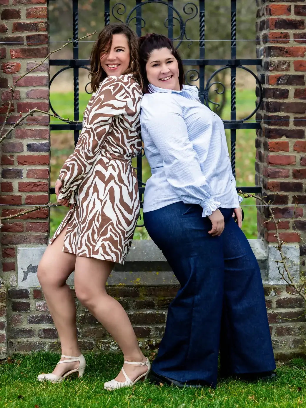 Deux femmes portant des vêtements CEDRAT - La chemise casual chic aux nombreuses options, devant une structure en brique.