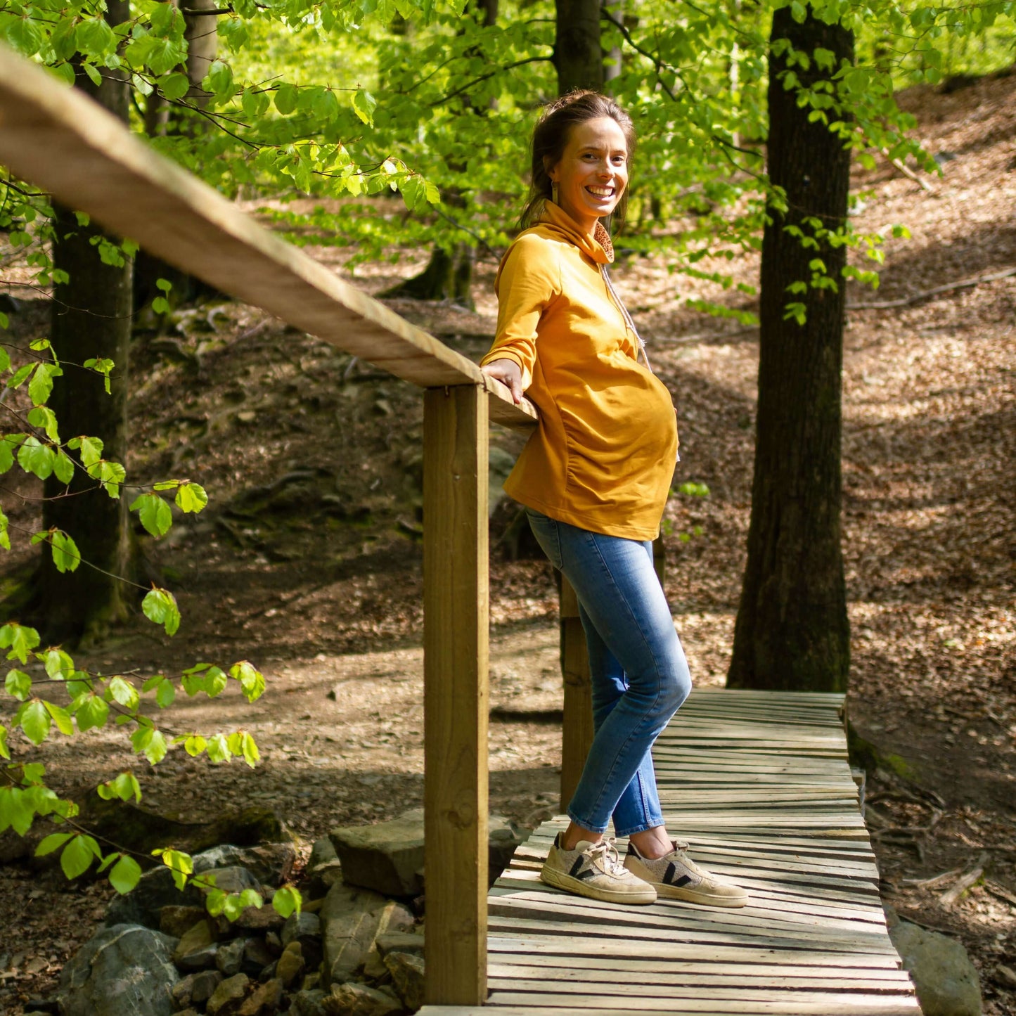 Femme enceinte portant "CHATAIGNE - LE sweat aux 32 versions" sur un pont en forêt, patron de couture pdf à télécharger.