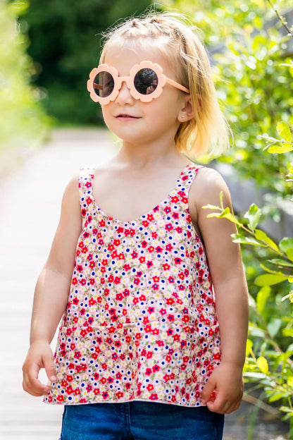 Enfant portant CLEMENTINE - Le top et la robe d'été, patron de couture pdf à télécharger, vêtement fleuri, lunettes de soleil roses.
