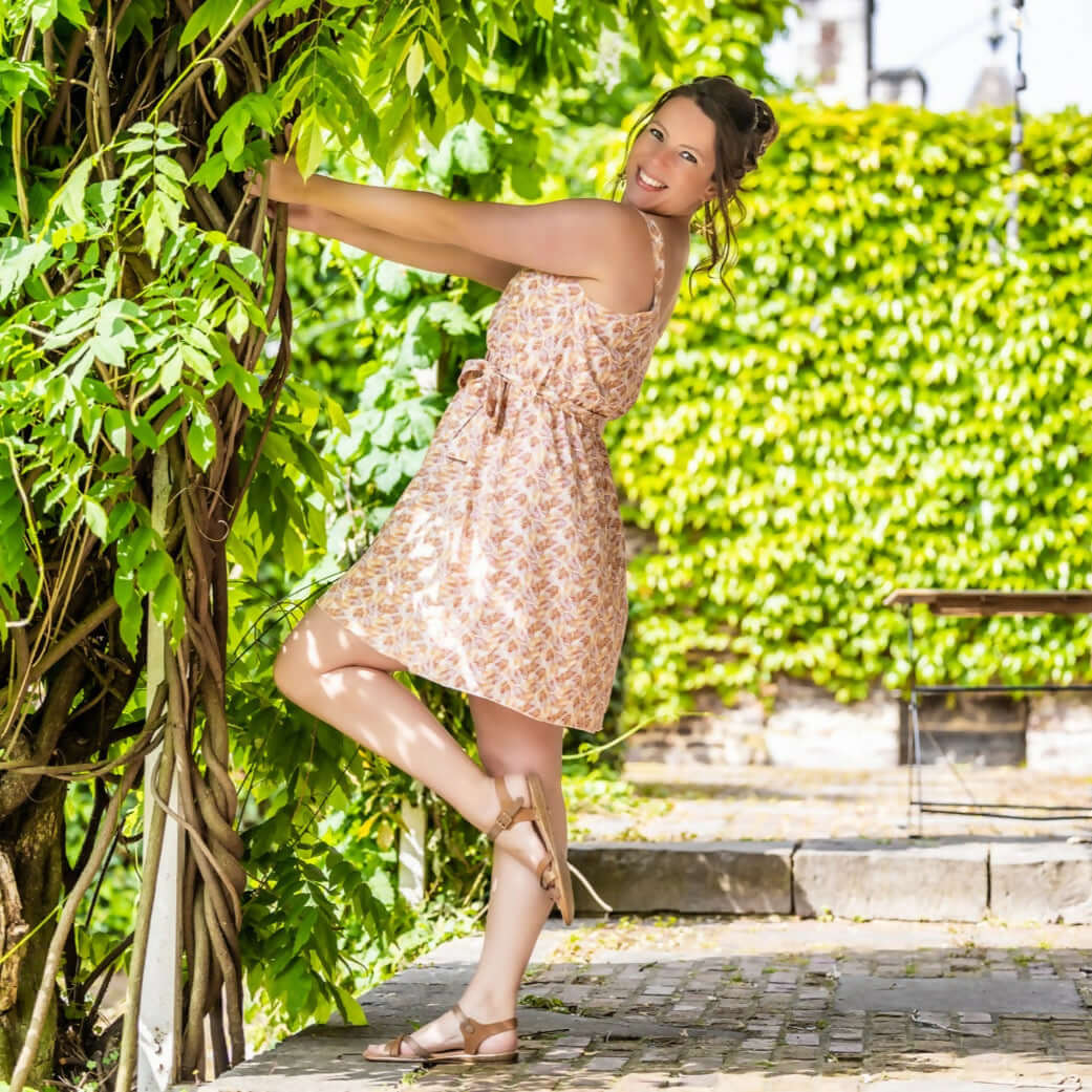 Femme portant la CLEMENTINE - Le top et la robe d'été, patron de couture pdf à télécharger, dans un jardin ensoleillé