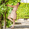 Femme portant la CLEMENTINE - Le top et la robe d'été, patron de couture pdf à télécharger, dans un jardin ensoleillé