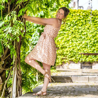 Femme portant la CLEMENTINE - Le top et la robe d'été, patron de couture pdf à télécharger, dans un jardin ensoleillé