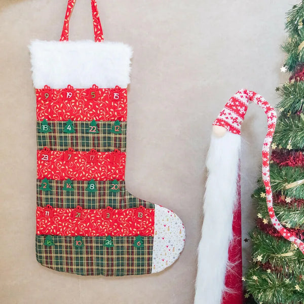 Calendrier de l'avent chaussette de Noël en tissu, patron de couture PDF à télécharger, suspendu près d'un sapin décoré.