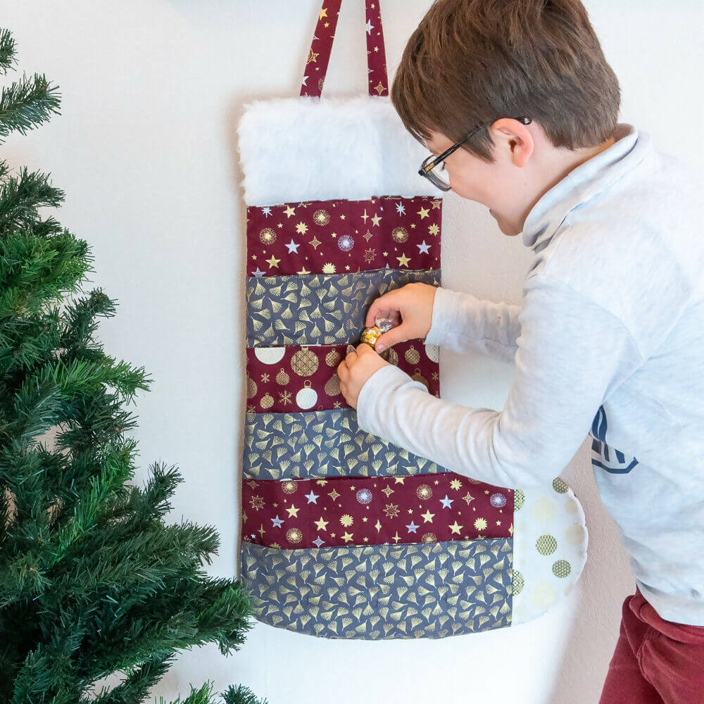 Calendrier de l'avent chaussette de Noël avec patron de couture pdf à télécharger, enfant découvrant une surprise. Zéro déchet.