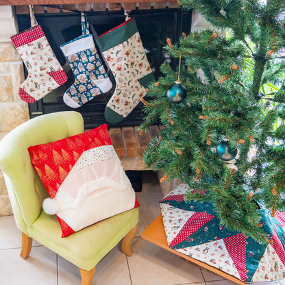 Chaussettes de Noël suspendues au-dessus d'un fauteuil vert, décorations festives autour d'un sapin de Noël.