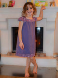 Enfant portant une chemise de nuit violette debout devant une cheminée, illustration pour patron de couture pdf à télécharger Chemise de nuit SONGE.