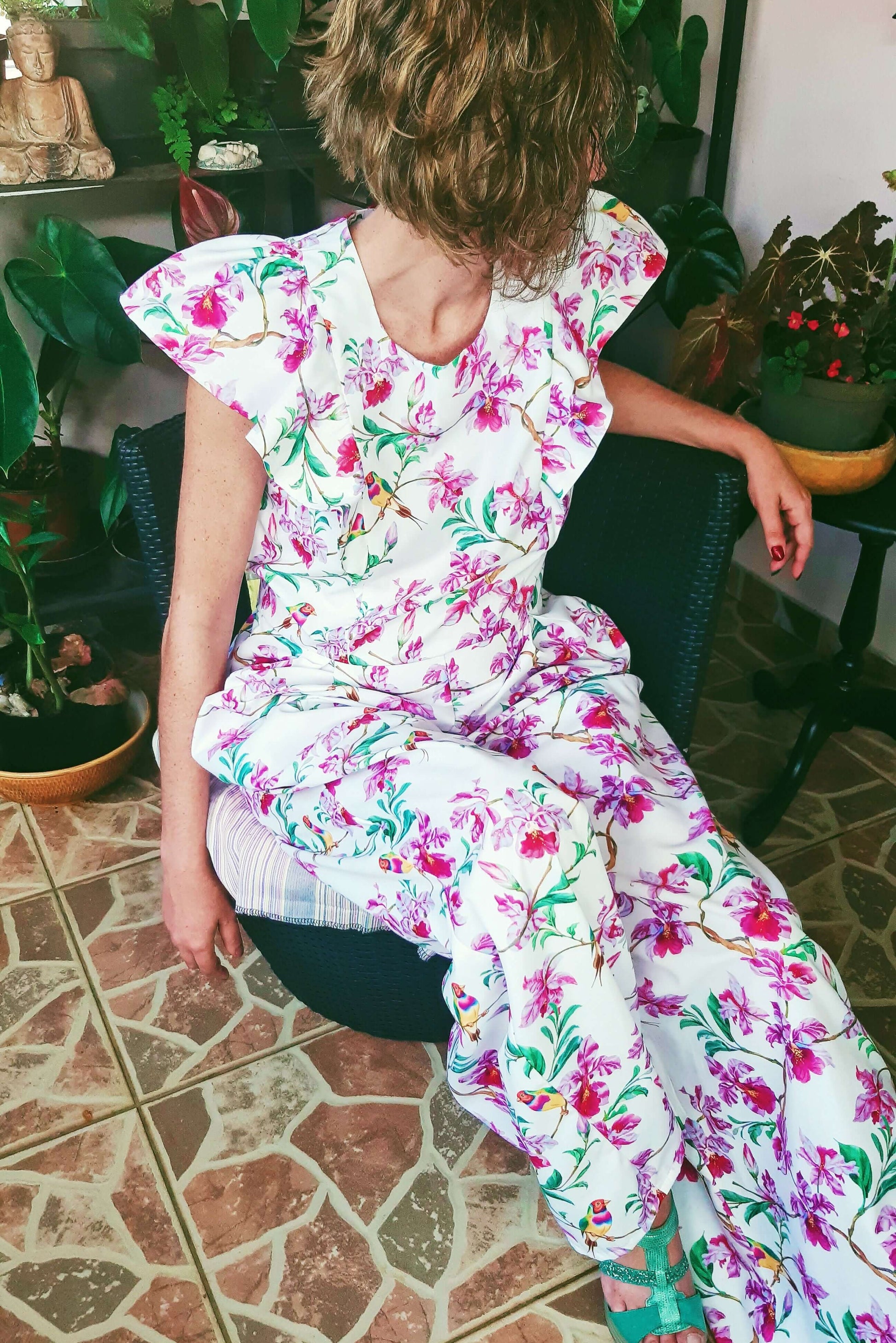 Femme portant la Combinaison Pantalon/Short Nephtys - T36 à 50, design floral, assise sur une chaise. Patron de couture PDF à télécharger.