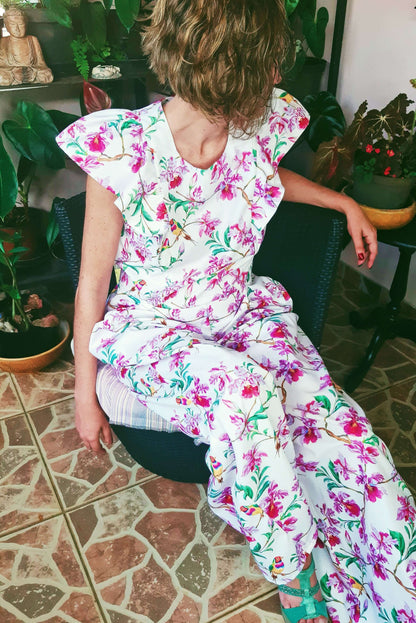 Femme portant la Combinaison Pantalon/Short Nephtys - T36 à 50, design floral, assise sur une chaise. Patron de couture PDF à télécharger.