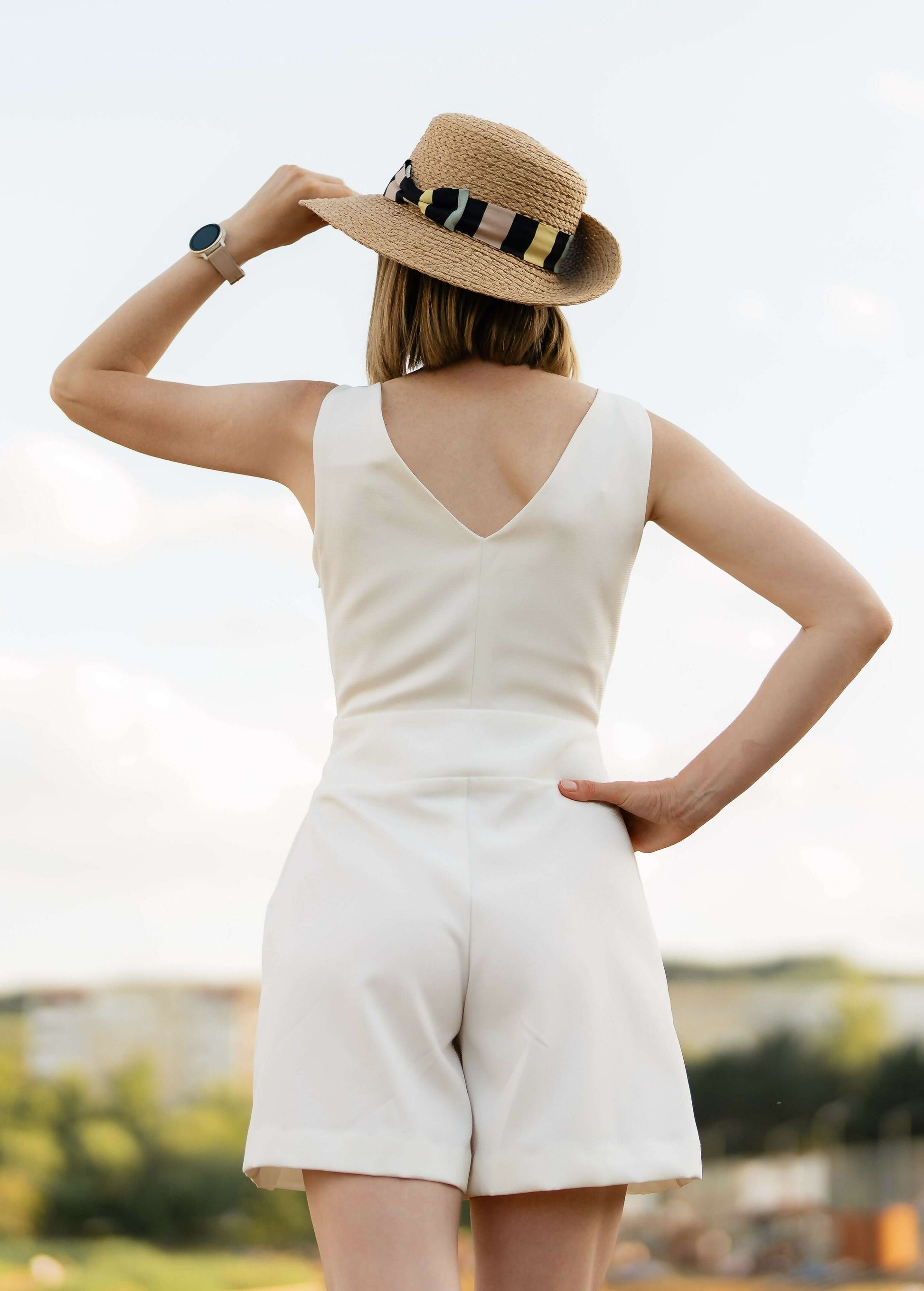 Femme en combinaison d'été blanche portant un chapeau, représentant le patron PDF "Combinaison - XS/XL - MAGNOLIA" de MUNA Patterns.