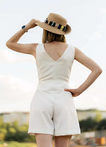 Femme en combinaison d'été blanche portant un chapeau, représentant le patron PDF "Combinaison - XS/XL - MAGNOLIA" de MUNA Patterns.
