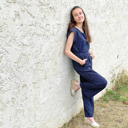 Femme portant la Combinaison, pantalon, 34 au 56, 4 statures – Vanille, patron de couture pdf à télécharger, adossée à un mur.