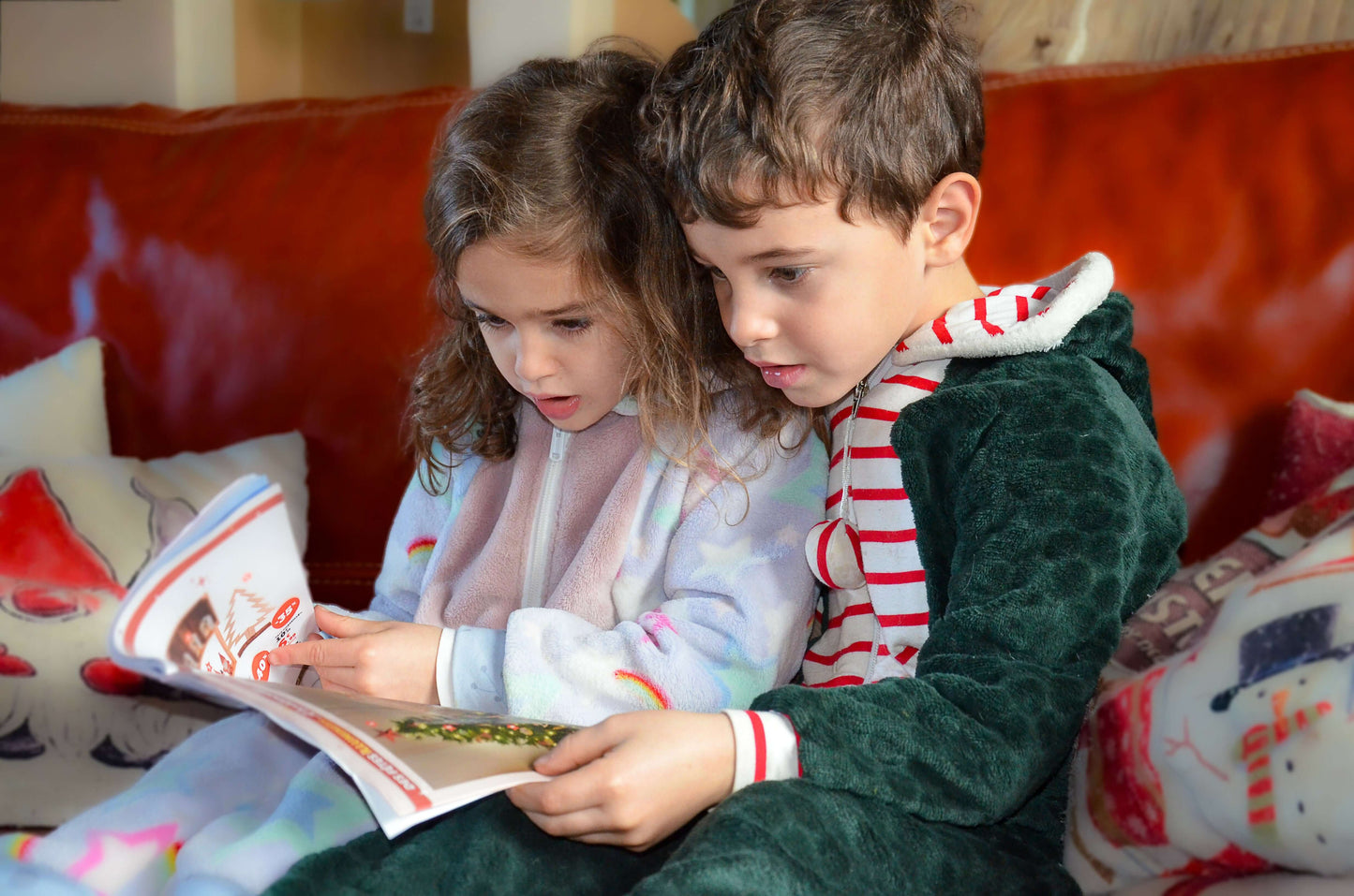 Deux enfants portant une Combinaison/Surpyjama PAPILLOTE, lisant un magazine, idéal pour l'hiver et patron de couture pdf à télécharger.