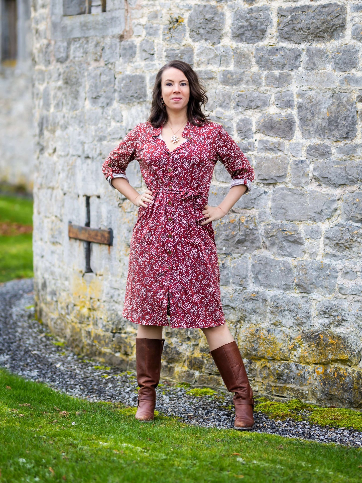 Femme portant DRAGON - La chemise ou robe pour toute la famille, patron de couture pdf à télécharger, devant mur en pierre.