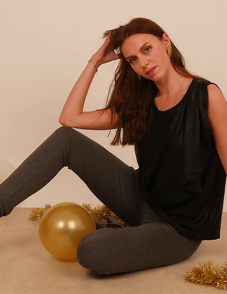 Débardeur Cara noir porté par une femme, assise avec un ballon doré, idéale pour une tenue de fête et couture personnalisée.