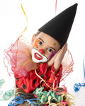 Enfant déguisé en clown avec chapeau pointu et collerette colorée, prêt pour le carnaval.