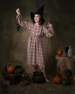 Fille en déguisement de sorcière avec chapeau, posant avec un rat en plastique, décor d'Halloween.