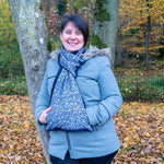 Femme souriante portant une écharpe avec manchon Baie rose, en pleine nature automnale.