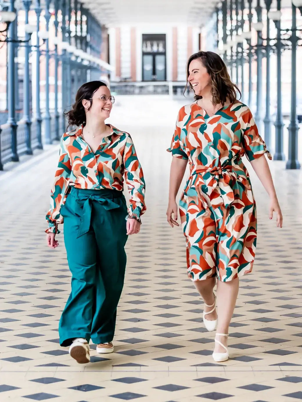 Deux femmes portant FIGUE - La blouse parfaite avec un patron de couture pdf à télécharger, en marchant dans un hall élégant.