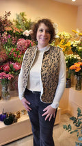 Femme portant un Gilet de Berger Cérès, devant un fond de fleurs colorées, look tendance et décontracté.