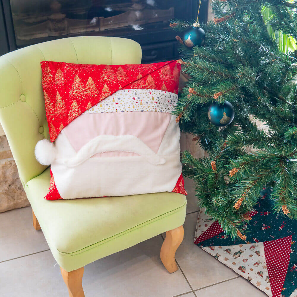 Housse de coussin Père Noël festive sur un fauteuil vert, idéale pour décorer votre salon pendant les fêtes.