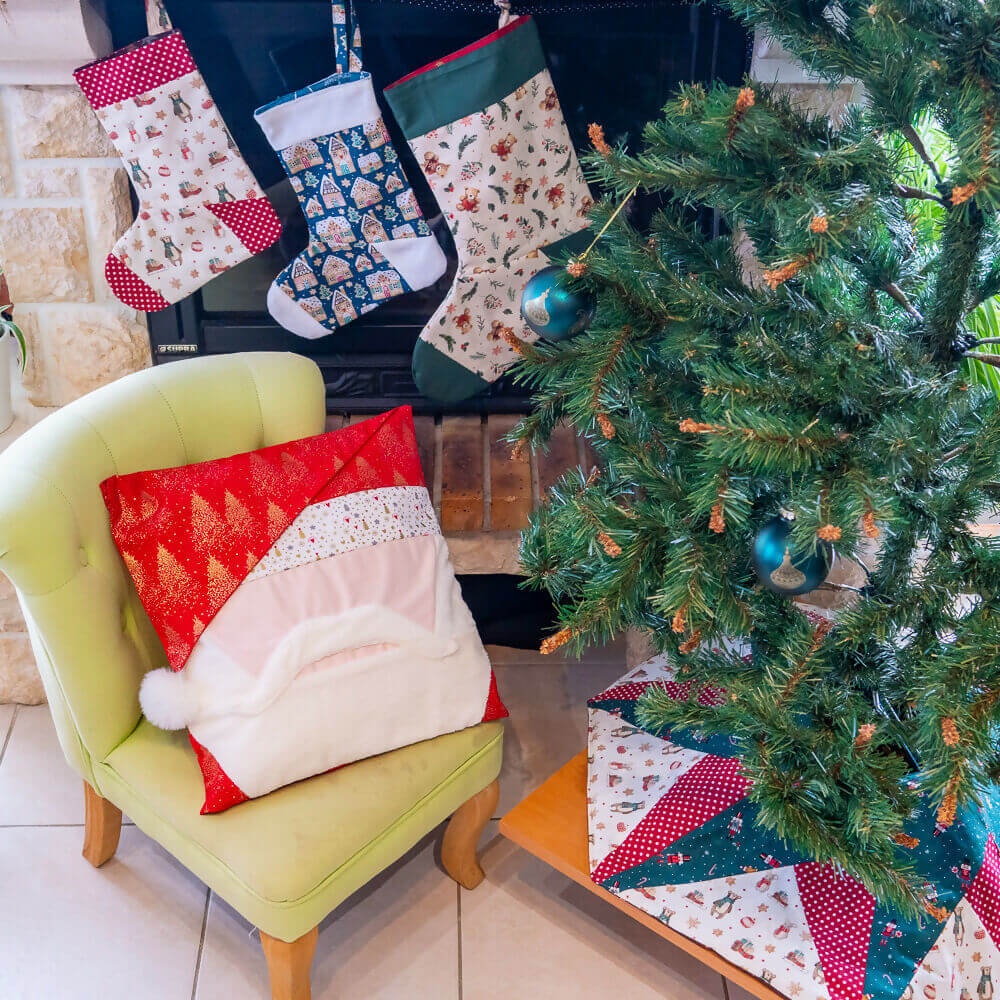 Housse de coussin Père Noël sur un fauteuil vert, décorée pour Noël avec une cheminée et des chaussettes suspendues.